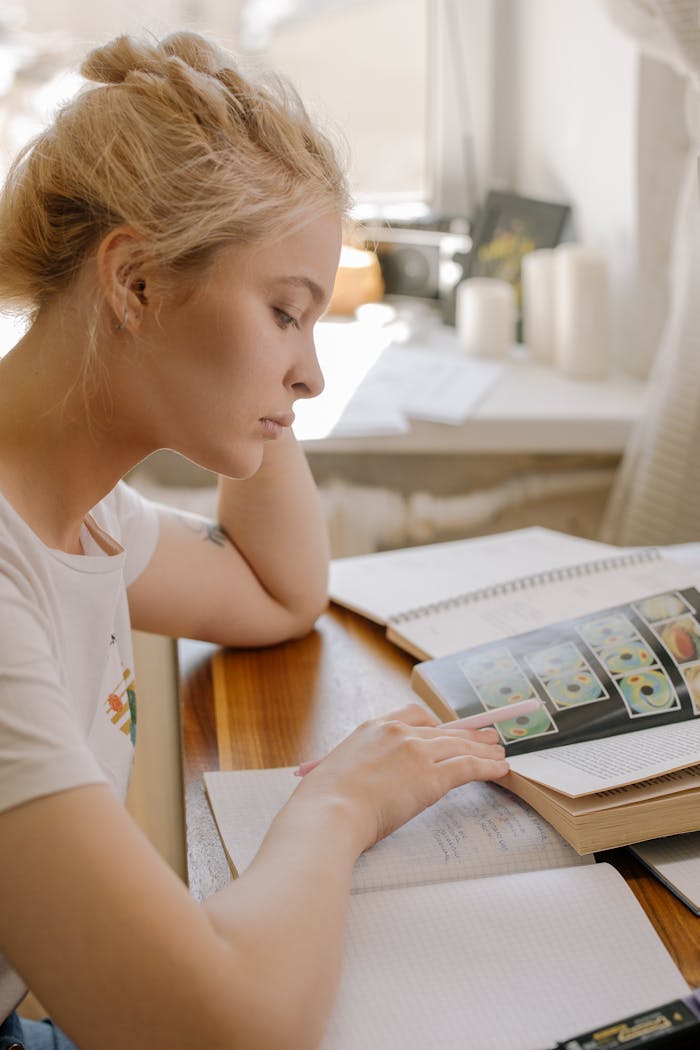 why-choose-us Focused young woman studying at home by the window with books open, illustrating a learning environment.