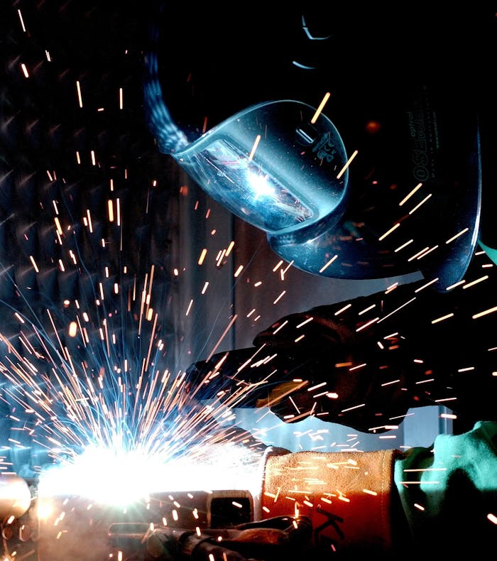 digital A focused welder works with metal in an industrial setting, creating vibrant sparks.